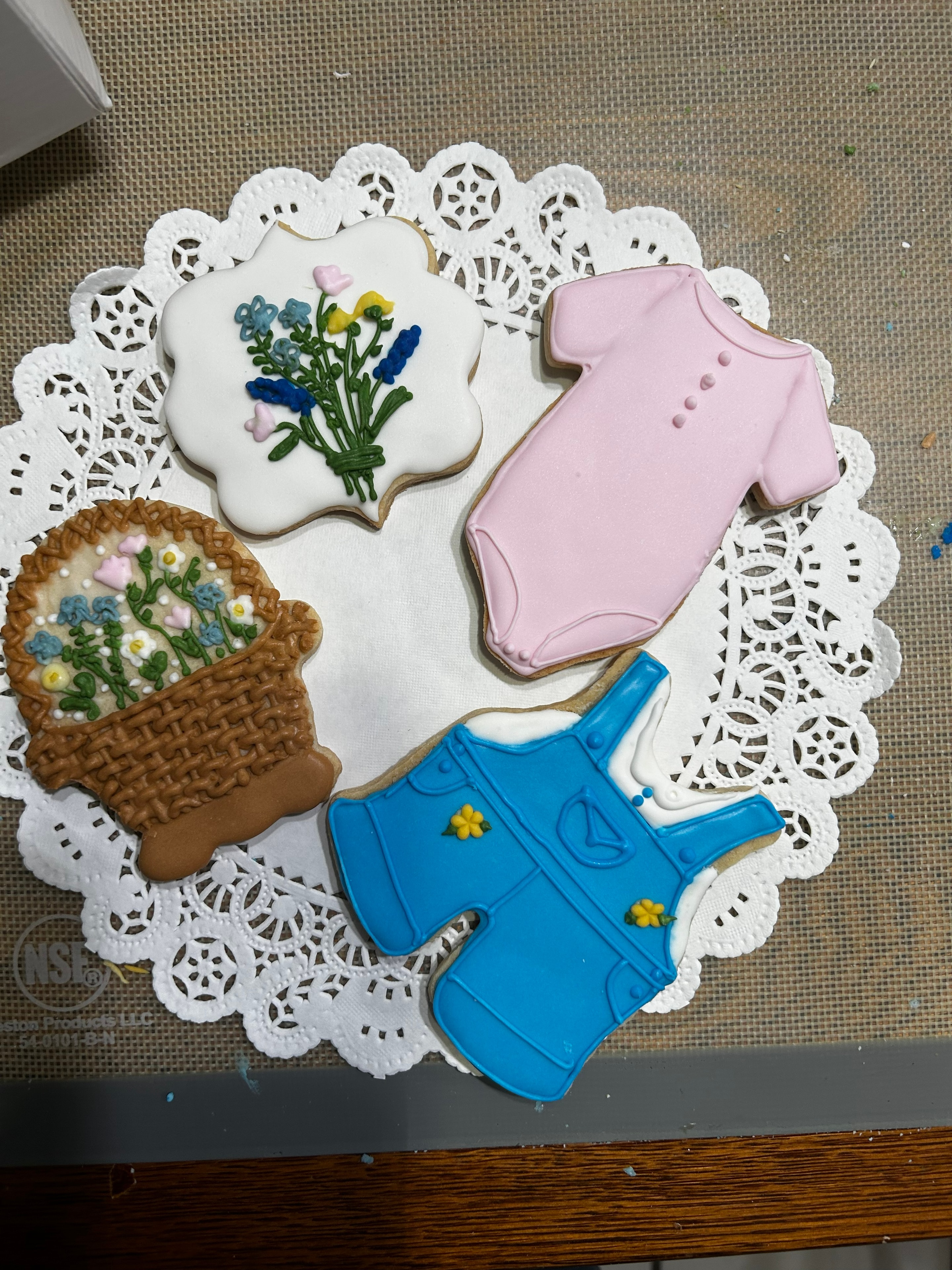 Baby shower cookies — floral bouquet, pink onesie, and blue overalls