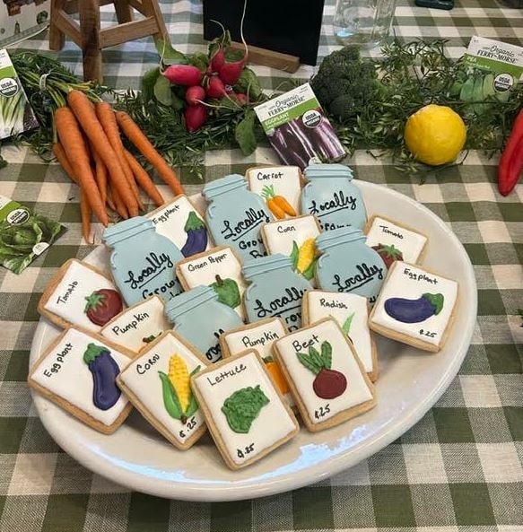 Garden themed cookies shaped as seed packets and vegetables — carrots, corn, eggplant, tomatoes