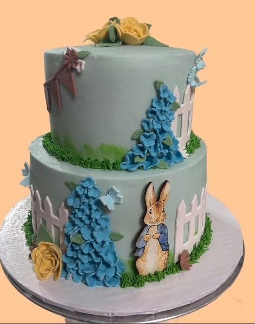 Peter Rabbit two-tier birthday cake with garden fence and hydrangeas