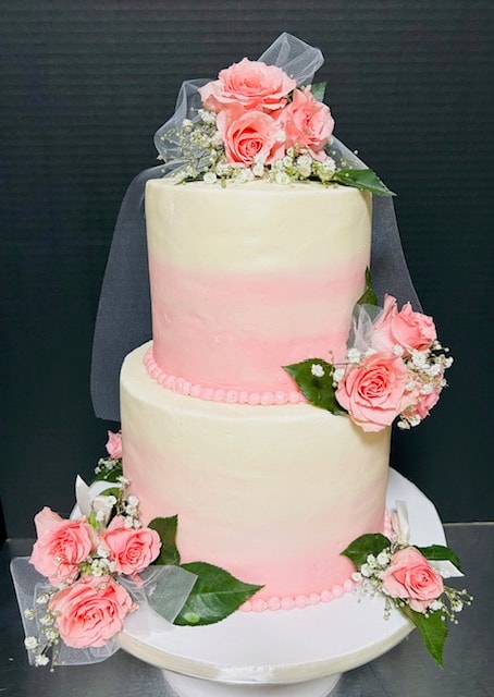 Two-tier wedding cake with fresh pink roses and veil topper