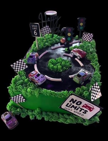 Race track birthday cake with toy cars and No Limits Just Speed sign