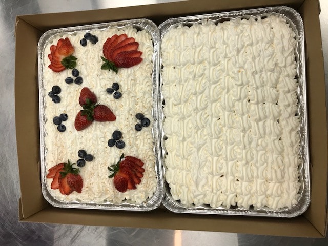 Two berry sheet cakes with whipped cream frosting, strawberries and blueberries