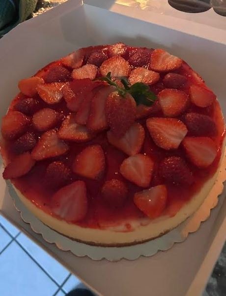 Strawberry cheesecake topped with fresh glazed strawberries in bakery box