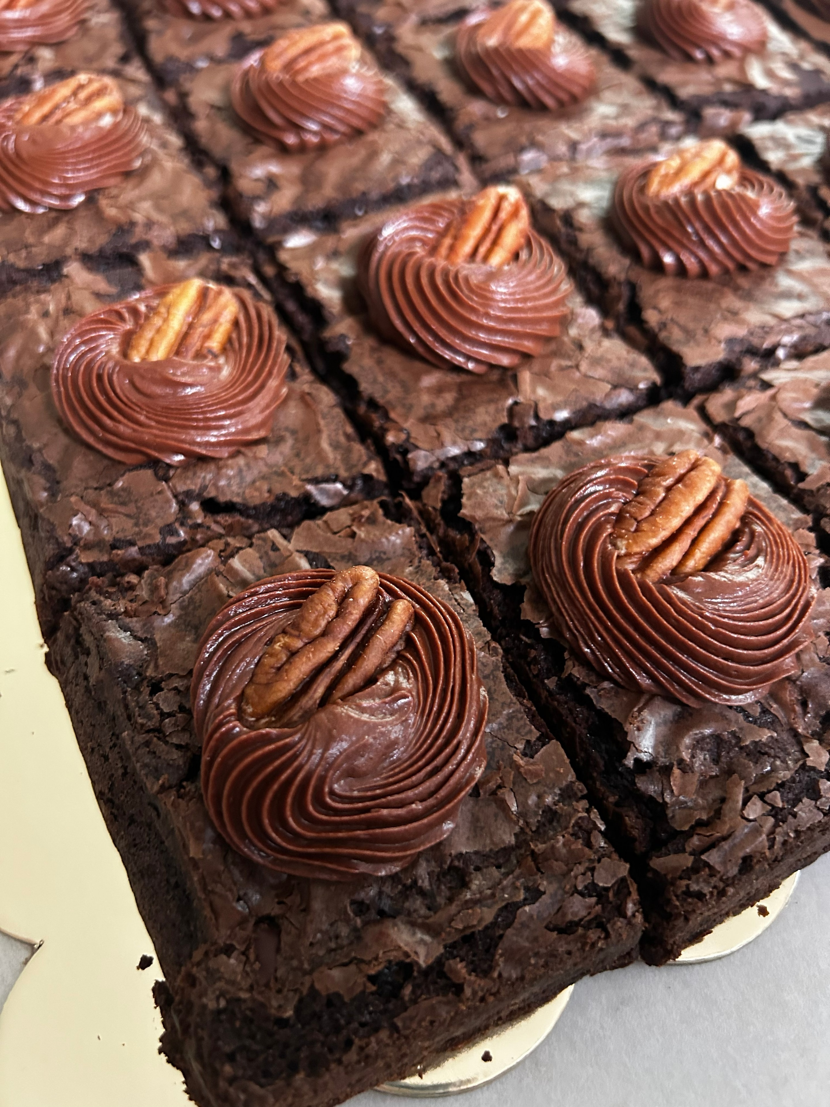 Pecan brownies with chocolate frosting rosettes and whole pecans on top