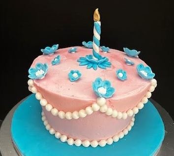 Un-birthday pink and blue floral cake with candle