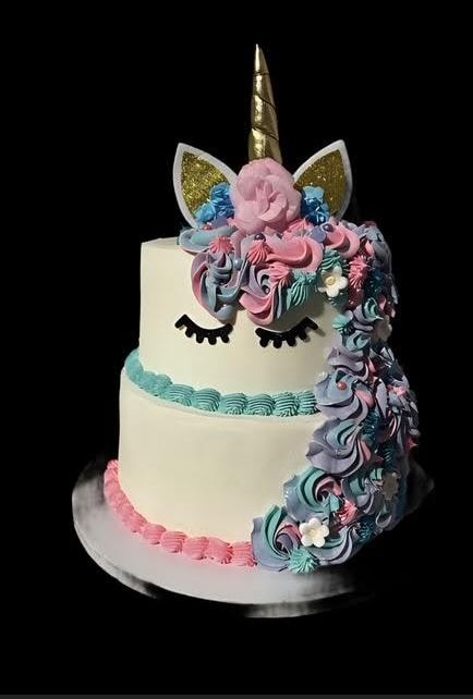 Two-tier unicorn cake with gold horn and pastel swirls