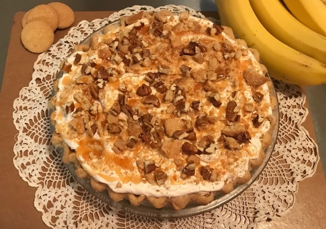 Banana caramel pie topped with whipped cream and pecans