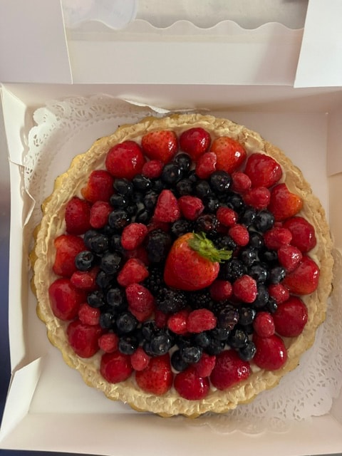 Fresh berry tart with strawberries, raspberries and blueberries in bakery box