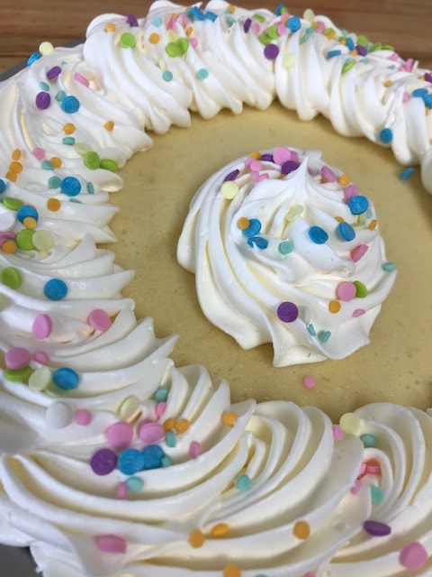 Cream pie with whipped rosettes and colorful confetti sprinkles
