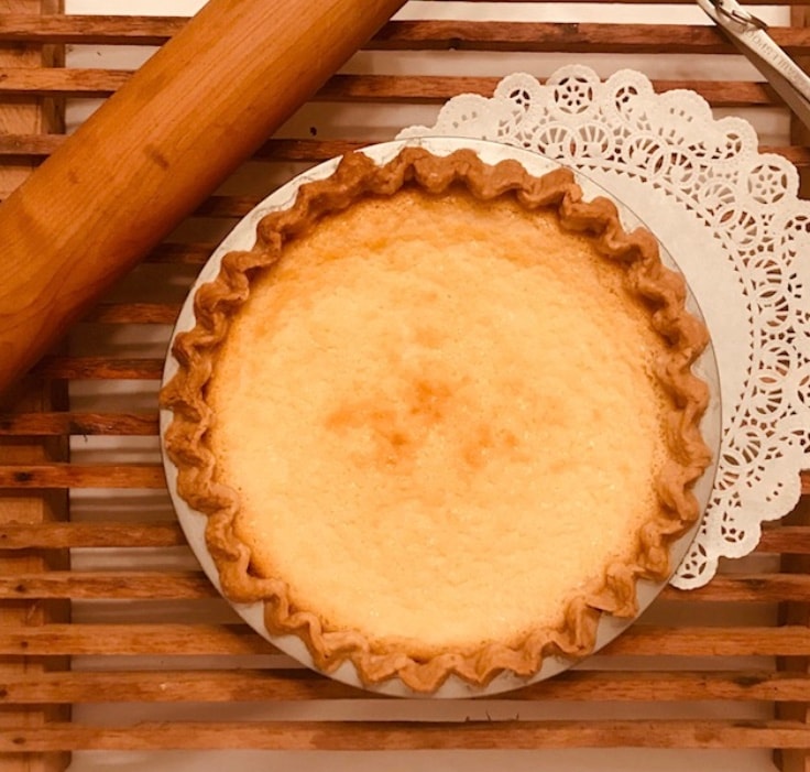 Classic sugar pie with crimped crust beside a rolling pin